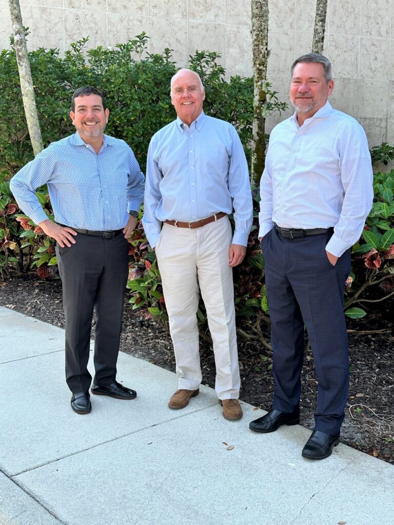 Three men standing outside smiling